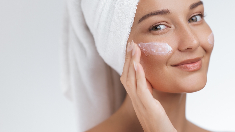 caucasian,woman,with,glowing,skin,and,white,towel,applying,moisturizing
